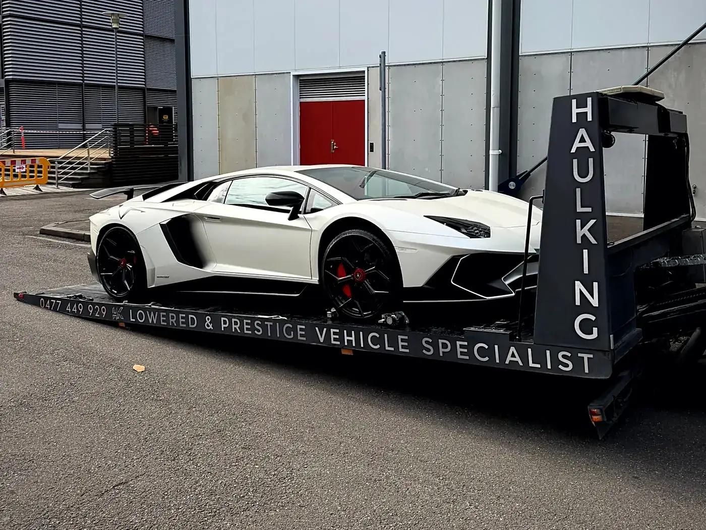 White Lamborghini Aventador secured on Haul King's open low-angle tray